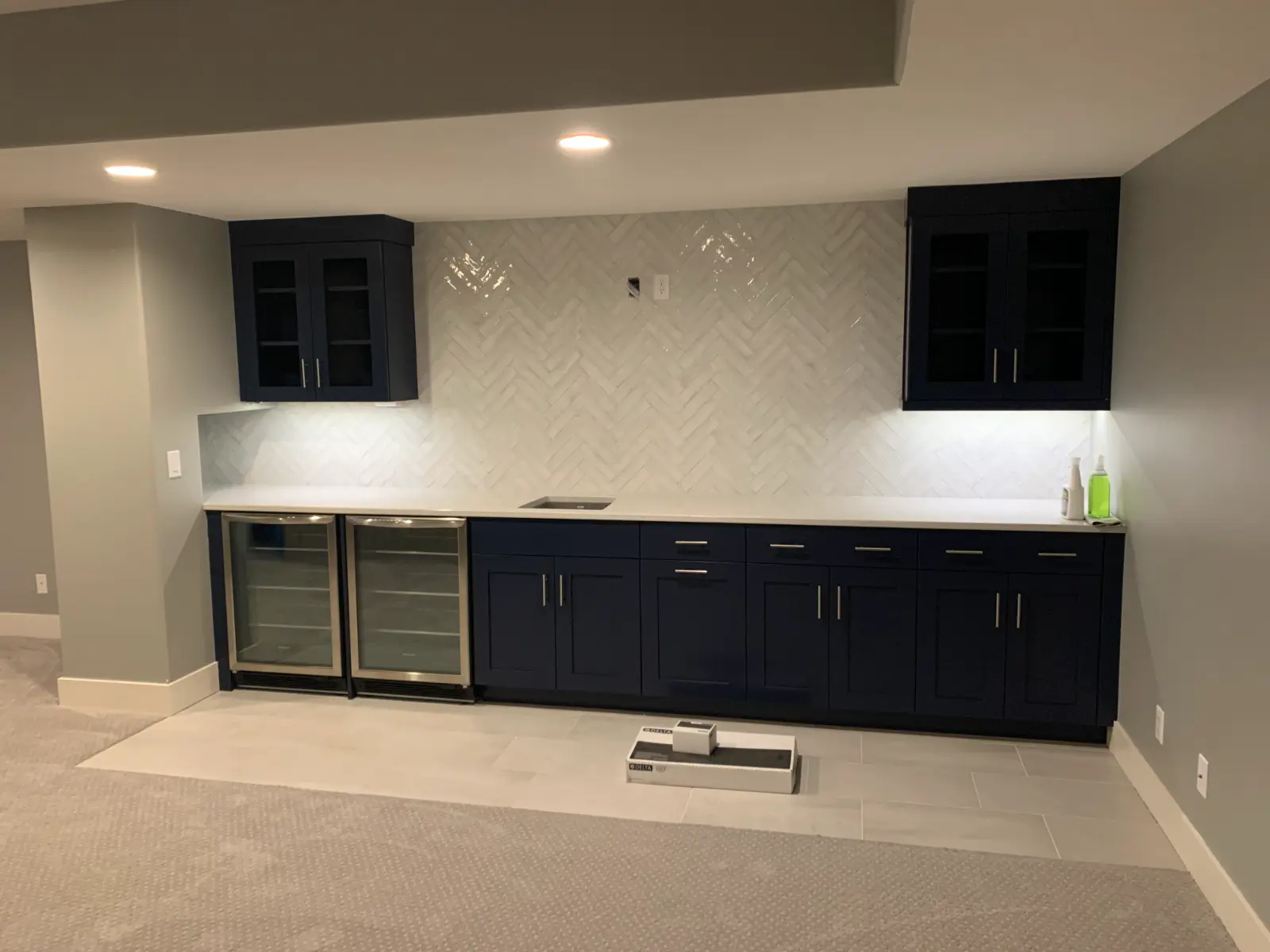 Rutford basement wet bar with navy cabinetry and herringbone tile